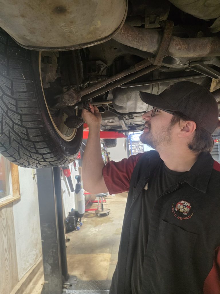 Technician inspecting suspension parts on the lift at TinJToo Auto Repair
