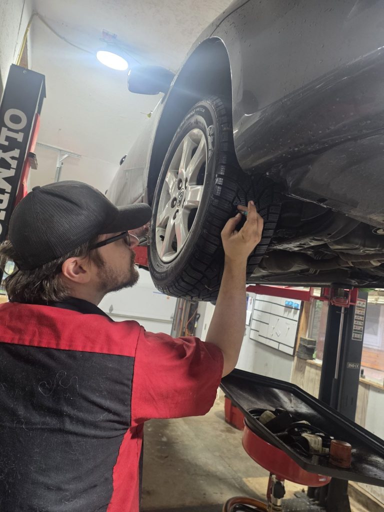 Technician checking a wheel and tire on the lift at TinJToo Auto Repair
